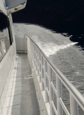 Tırabzanlı bir teknenin yan tarafında. Ve suyun derin mavi göldeki hareketi.