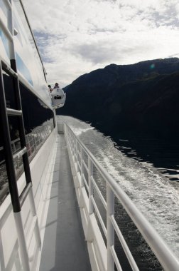 Mavi bir su gölünde yelken açan bir teknenin güvertesinde. parmaklıklarla.