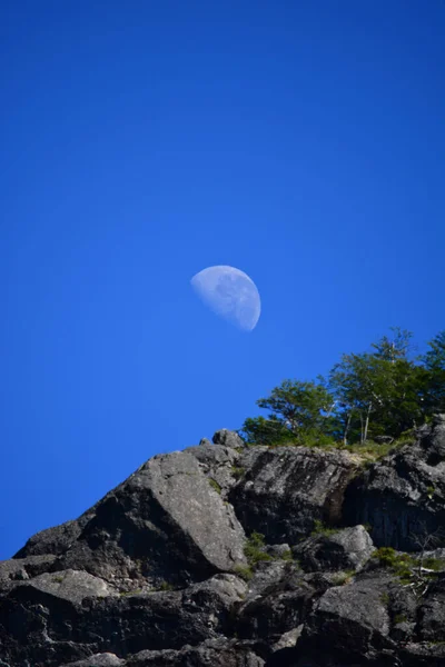 The moon on a blue sky, behind the stone mountain