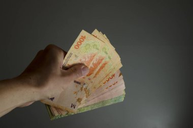 Bin beş yüz Arjantin pesosu şekillendirilmiş bir hayran, gri arka planda ev ekonomisi tasarrufu