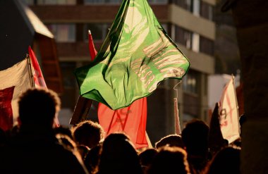 İnsanlar bayraklarla ışığa karşı gösteri yapıyor ve bir şeyler talep ediyorlar.