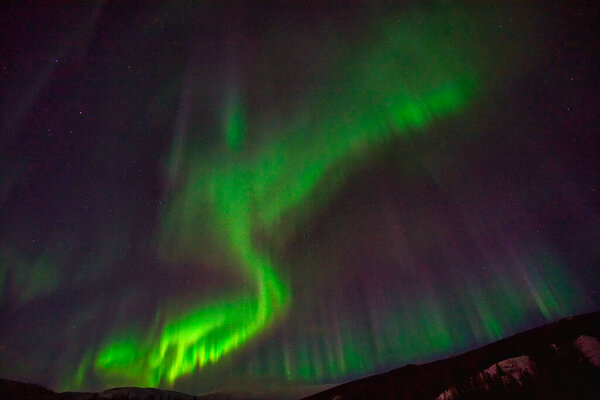 Aurora borealis в ночном небе. Светлые цвета зелёные, жёлтые и красные. Фотография сделана на Аляске, США 17 марта 2016 года