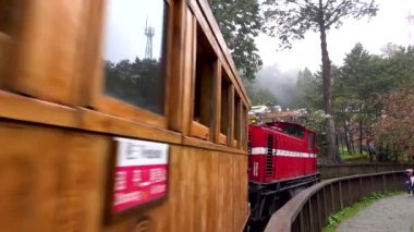 Orman parkındaki yürüyüş treni. Kırmızı bir lokomotifi var. Tren, kiraz çiçeği, ağaç, bulut. Tayvan 'ın Chiayi ilçesindeki Alishan Ulusal Orman Dinlenme Alanı' nın çeşitli manzaraları. 21 Mart 2021.