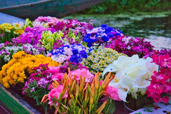 Flowers on shikara boat at floating market in morning. View of Dal Lake in Srinagar, Kashmir State, India. June 2018