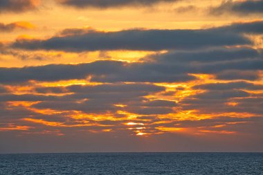 Sun rays passing through dark clouds. The unpredictable drama of the sky at sunset. A view from a tourist cruise ship sailing in the North Pacific Ocean. June 2019