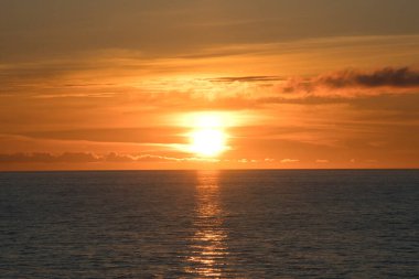 Kanada Boğazı 'nın üzerinde gün batımı. Denizin turuncu parıltısı. Gezici bir yolcu gemisinden manzara.