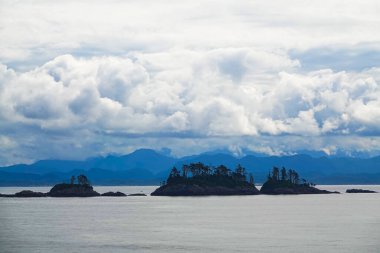 The lake has some small islands. White clouds look like a distant island. View from a sightseeing cruise ship.