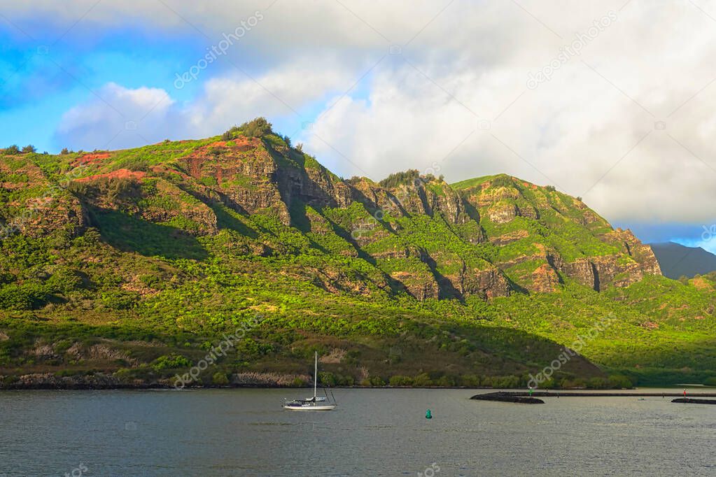 Two sailboats on the coast of Kauai.  here are green mountains in the background. Hawaii, USA. June 2019.