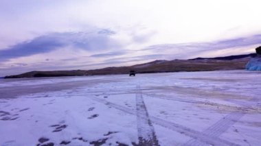 Minibüs donmuş gölün üzerinde sürüyordu. Gölde çok sayıda tekerlek izi var. Olehun Adası 'nın güney hattı, Baykal Gölü, buz saçağı manzaralı. - Rusya. Ocak 2019