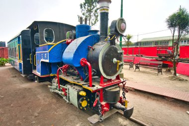 Darjeeling, Batı Bengal, Hindistan. - 24 Kasım 2019, Darjeeling Himalaya Demiryolu. UNESCO Dünya Mirası Alanlarından biri. Tarihi lokomotif. Lokomotif siyah, mavi ve kırmızıya boyanmış. Ziyaretçiler görsün diye parkta sergileniyor..