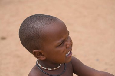 Himba kabilesi, Kuzey Namibya, 14 Ekim 2019. Boynunda kolyeler olan Himba çocukları ziyaretçilerle etkileşim halindedir. Himba kabilesinin geleneksel yaşam sahnesini ziyaret ediyoruz..