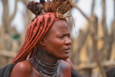 Himba kabilesi, Kuzey Namibya, 14 Ekim 2019. Himba 'lı kadın kırmızı örgü takıyor. Saç kremi yapmak için pudra, süt yağı, tereyağı, kül ve vanilya karışımı kullanıyorlar. Saçlarına uygulanır..