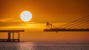 Spectacular sunset over the nearly completed Danjiang Bridge in Tamsui New Taipei Taiwan during early autumn. Golden orange and reddish pink dreamlike sky.