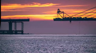 Dramatic colorful twilight over the nearly finished Tamkang Bridge construction in Tamsui New Taipei Taiwan. Red orange and pink dreamlike sky.