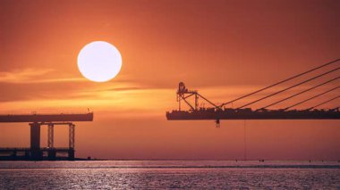Dreamy sunset over Tamkang Bridge in Tamsui Taiwan, with boats passing and vibrant clouds in early autumn.