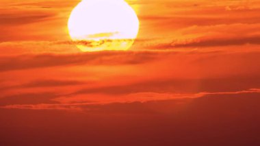 Dramatic sunset partially hidden by clouds over Dashan in New Taipei Taiwan, featuring vibrant orange red sky in early autumn dusk.