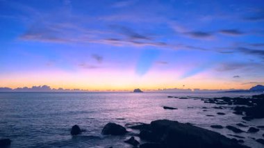 Stunning blue orange yellow sky before sunrise over Keelung Islet at Wanli New Taipei Taiwan, with calm waves in early autumn dawn.