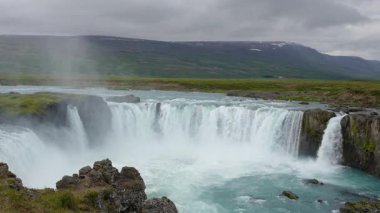 Godafoss Şelalesi İzlanda Tanrılarının Şelalesi geniş çağlayanı ve turkuaz suyu bulutlu bir günde bazalt kayalıkların altında gösteriyor..