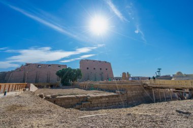 Luxor, Mısır - 18 Ocak 2025: Karnak Tapınağı 'nın devasa sütun girişi ve antik kalıntıları üzerinde açık bir bahar sabahı güneş ışığı patlamaları meydana geldi. Ziyaretçiler geniş alanı keşfederken görülüyor..