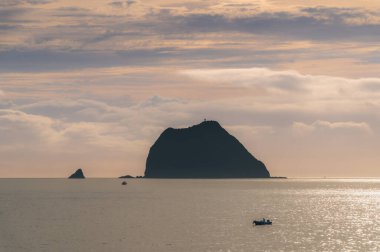 Keelung, Tayvan 'da sakin bir sabah, heybetli Keelung Adası yakınlarındaki sakin denizi aşan bir balıkçı teknesi gibi. Su güneşin sıcacık, altın ışığını yansıtır..