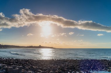 Çarpıcı yaz günbatımı zamanı Shihmen 'den Pasifik Okyanusu' na çakıl taşı plajı ve tepenin üzerindeki radar istasyonu siluetiyle New Taipei Tayvan sahiline kadar uzanıyor..
