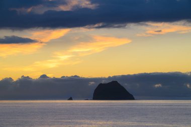 Jiulong Adası siluetinin düş gibi turuncu ve altın rengi gökyüzüne vurduğu Keelung Outer Waishan 'da büyülü gün doğumunu yakalayın. 10 Haziran 2025 'te balıkçı tekneleri ve deniz manzarası ile çekilmiştir..