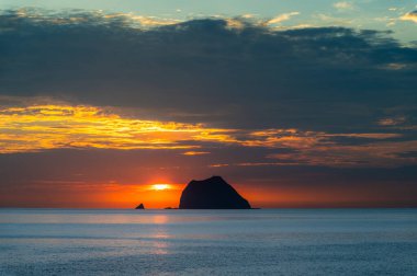Altın gün doğumu Waimushan, Tayvan açıklarında okyanusu aydınlatır. Keelung Adası ve canlı yaz gökyüzünün altında gölgeli balıkçı tekneleri..