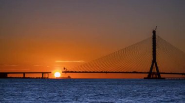 Canlı günbatımı siluetleri. Tamsui Yeni Taipei 'de inşa halindeki Danjiang Köprüsü' nde gemi ve parlayan ufuk çizgileri..