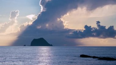 Wanli Bölgesi Tayvan 'ında sabah saatlerinde parıldayan okyanus yüzeyinde hareket eden beyaz kümülüs bulutlarının parlak geniş bir görüntüsü karanlık kayalık sahilde balık tutan bir kişi görülüyor..