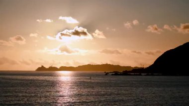 Bir yolcu gemisi sonbahar sabahı şafağında Dawulun yakınlarındaki Keelung Limanı 'na doğru yola çıkıyor. Altın gökyüzü ve deniz feneri silueti Sakin denizde parıldıyor.