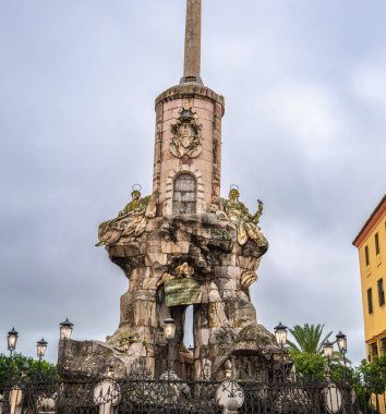 Başmelek Raphael 'in altın heykeli ile kaplanmış Barok zafer sütunu Roma Köprüsü' nün yanında ve İspanya 'da bulutlu gökyüzünün altında Cordoba Katedrali' nin yanında duruyor..
