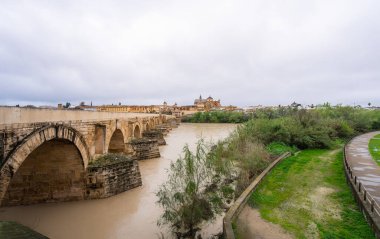 Cordoba 'nın antik Roma Köprüsü Guadalquivir Nehri boyunca uzanır ve İspanya' daki dramatik bulutlu gökyüzünün altındaki tarihi Mezquita 'ya uzanır..