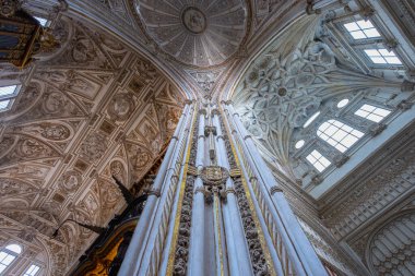 Cordoba, İspanya - 13 Mart 2025: Tarihi anıtın içindeki yüksek beyaz sütunlar ve karmaşık Rönesans mahzenlerinin alçak açılı görünümü.