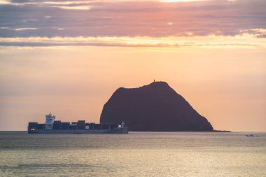 Tayvan, Keelung Waimushan 'daki Jilong Adası' ndan önce hareket eden sakin gemi siluetini izleyin. 2025 yılında çekilen bu yaz sabahında turuncu gökyüzü, dalgalı su blokları ve sakin dalgalar yer alıyor..
