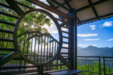 Tayvan 'ın Yuchi kasabasındaki Jinlongshan Gündoğumu güvertesinde dağ tasarımı olan sanatsal metal kapı. Güneş ışığı ve orman sakin bir sabah manzarası yaratır..