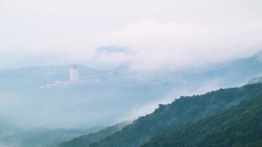 Tayvan 'ın Taipei kentindeki Datun Dağı' nın manzarası. Bir bahar sabahı hareket eden bulutlar ve sislerin arasından yükselen bir bina..