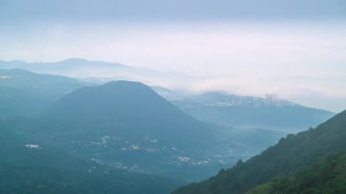 Tayvan 'ın Taipei kentindeki Datun Dağı manzaralı bir sabah manzarası, kayan tepeler, yemyeşil ormanlar ve kısmen hareket eden bulutlarla gizlenmiş bir köy.