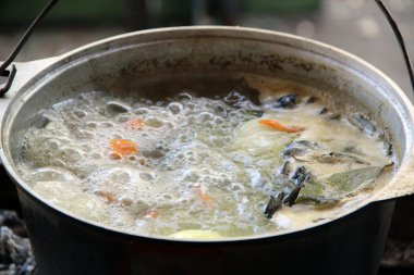 Balık likörü. Sıcak ve lezzetli nehir alabalığı ve sebze bulyonu. Sağlıklı ve lezzetli bir turist yemeği. Yemek ateşte pişiyor..