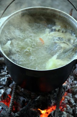 Balık likörü. Sıcak ve lezzetli nehir alabalığı ve sebze bulyonu. Sağlıklı ve lezzetli bir turist yemeği. Yemek ateşte pişiyor..