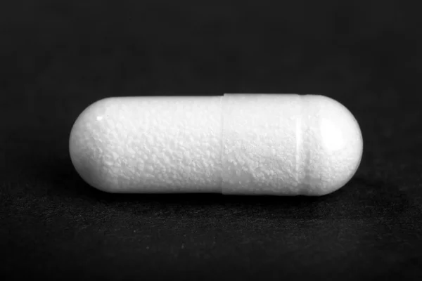 Witte pillen op zwart — Stockfoto