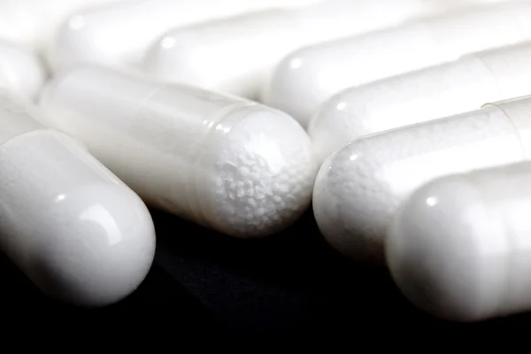 Белые таблетки на черном — стоковое фото