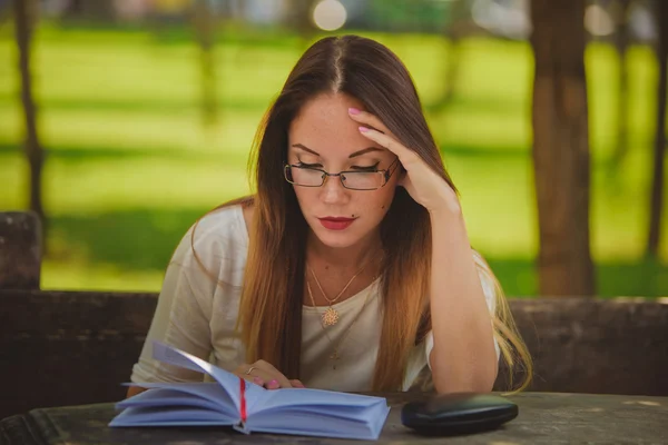 Tyttö kirjan lukeminen puistossa — kuvapankkivalokuva