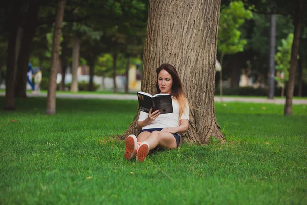 Mädchen mit Buch unter Baum — Stockfoto