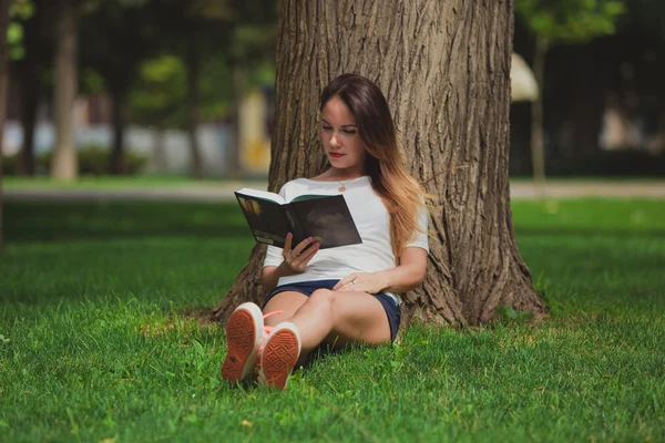 Κορίτσι με το βιβλίο κάτω από δέντρο — Φωτογραφία Αρχείου