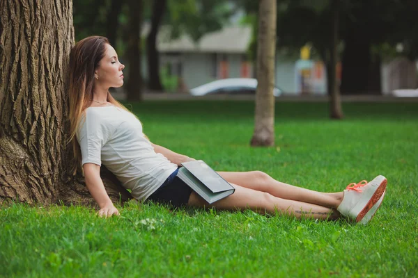 Mädchen mit Buch unter Baum — Stockfoto