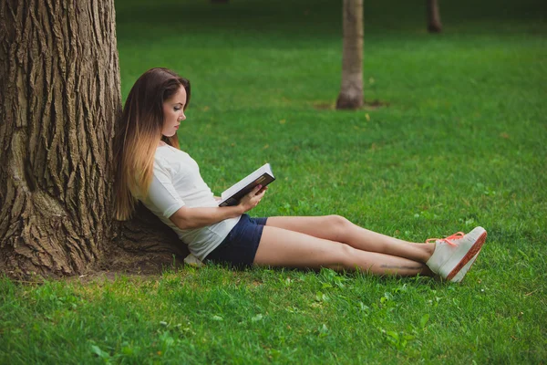 Mädchen mit Buch unter Baum — Stockfoto