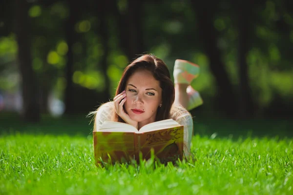 Tyttö kirjan nurmikolla — kuvapankkivalokuva