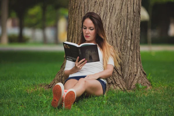 Mädchen mit Buch unter Baum — Stockfoto