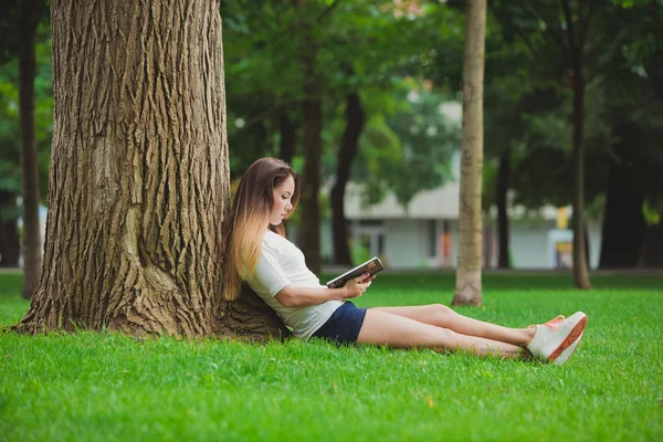 Mädchen mit Buch unter Baum — Stockfoto