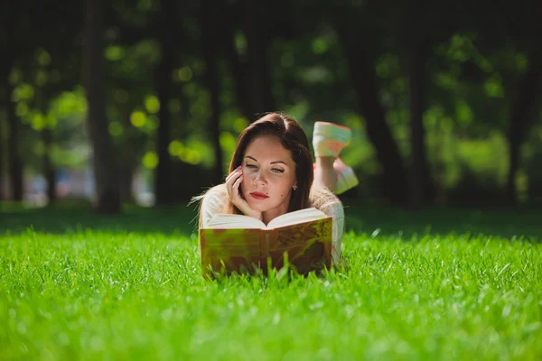 Tyttö kirjan nurmikolla — kuvapankkivalokuva